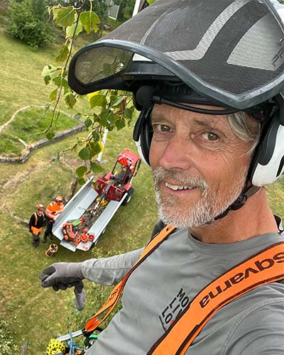 En man som tar en selfie uppe från ett träd han klättrat upp i för att sektionskapa trädet